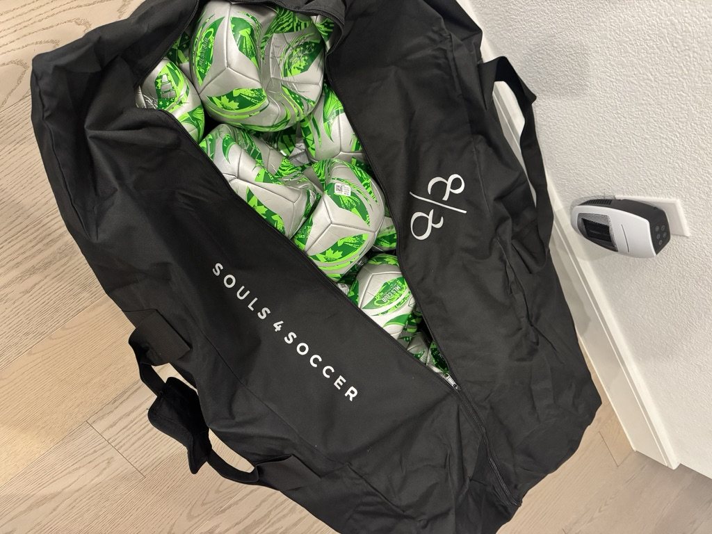 An 88 Souls 4 Soccer equipment bag packed with new green and silver soccer balls