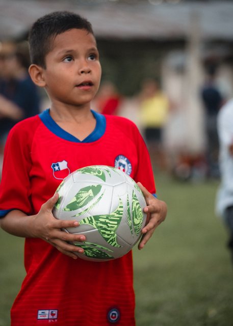 A young boy in a red jersey holding his new soccer ball
