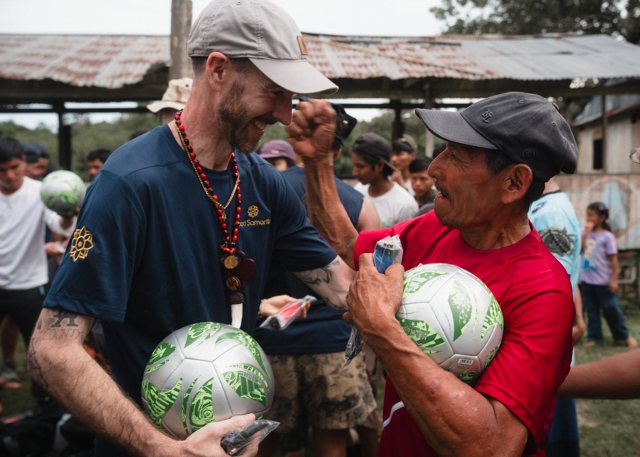 Two men celebrating with new soccer balls in their arms