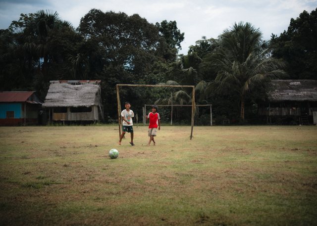 Two boys playing near a wooden goal at the edge of the rainforest