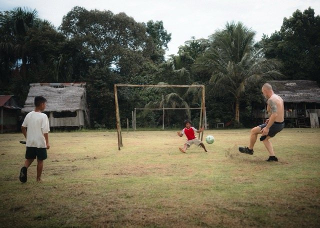 A team member shooting on a young goalkeeper diving between wooden posts