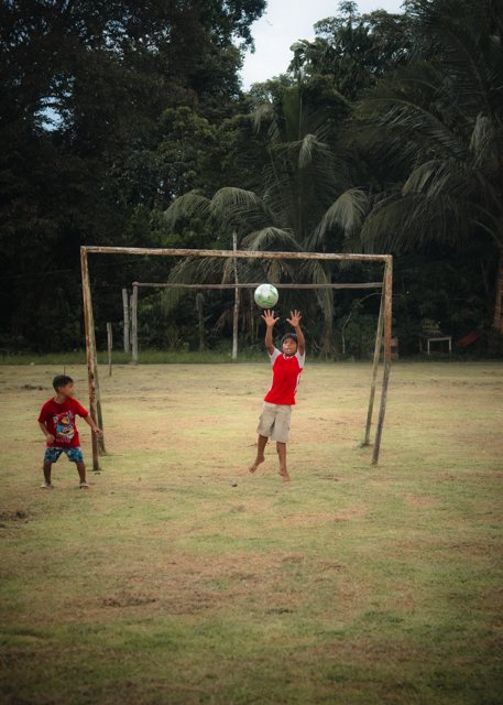 A boy leaping to head the ball in front of a wooden goal